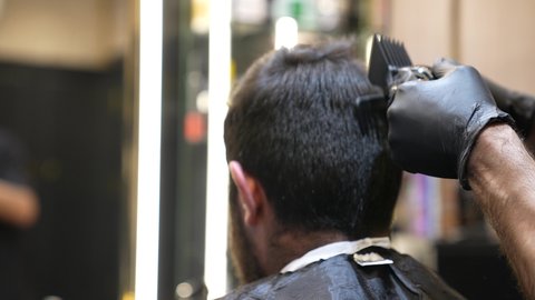 استخدام أدوات و معدات الحلاقة, تقديم خدمات العناية الشخصية، ممارسة مهنه الحلاقة, تصوير مقرب ليد حلاق عربي خليجي سعودي يقوم بحلاقة شعر الزبون باستخدام ماكينه الحلاقة