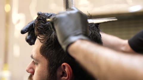 جلسة حلاقة حديثة، استعمال ادوات المقص و المشط, تقديم خدمات العناية الشخصية، الاهتمام بالشكل الخارجي، الممارسة مهنه الحلاقة, تصوير مقرب ليد حلاق عربي خليجي سعودي يقوم بحلاقة شعر الزبون