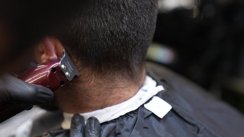 تقديم خدمات العناية الشخصية، الاهتمام بالشكل الخارجي، الممارسة مهنه الحلاقة, تصوير مقرب من الخلف لزبون عربي خليجي سعودي يقوم بحلاقة شعره فى صالون التجميل الرجالي