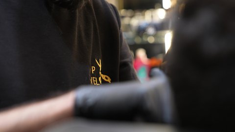 المحافظة على الأناقة والنظافة الشخصية، صالون تجميلي رجالي لتصفيف الشعر، تقديم خدمات العناية الشخصية, تصويرمقرب ليد حلاق عربي خليجي سعودي يرتدي يونيفورم الصالون يقوم بتصفيف  شعر الزبون