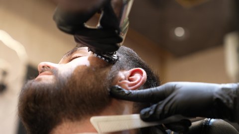 صالون تجميلي رجالي لتصفيف الشعر، المحافظة على الأناقة والنظافة الشخصية، تقديم خدمات العناية الشخصية, تصويرمقرب ليد حلاق عربي خليجي سعودي يقوم بحلاقة الذقن للزبون، صالون تجميلي رجالي