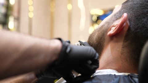 المحافظة على الأناقة والنظافة الشخصية، استعمال ماكينة الحلاقة و المشط، تقديم خدمات العناية الشخصية, تصويرمقرب ليد حلاق عربي خليجي سعودي يقوم بالحلاقة للزبون