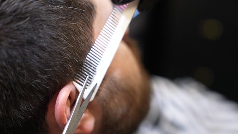 استعمال المقص لتحديد السوالف، تقديم خدمات العناية الشخصية, الاهتمام بالمظهر الخارجي و النظافة البدنية, تصويرمقرب ليد حلاق عربي خليجي سعودي يقوم بالحلاقة للزبون
