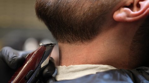 استعمال ماكينة الحلاقة لتحديد الذقن, تقديم خدمات العناية الشخصية, الاهتمام بالشعر و النظافة البدنية, تصويرمقرب ليد حلاق عربي خليجي سعودي يقوم بالحلاقة للزبون