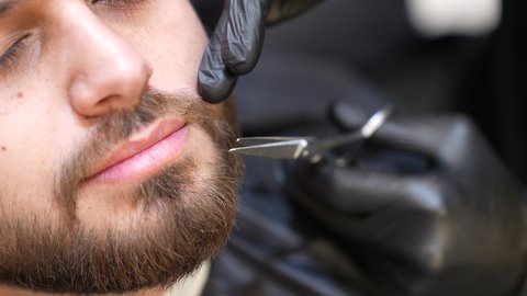 تقديم خدمات العناية الشخصية، استعمال المقص لحلاقة الذقن, الاهتمام بالشعر و النظافة البدنية, تصويرمقرب ليد حلاق عربي خليجي سعودي يقوم بالحلاقة للزبون