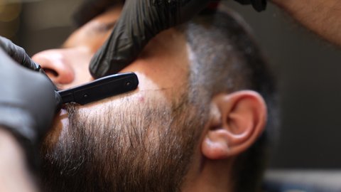 استعمال المقص و المشط لحلاقة الذقن, تقديم خدمات العناية الشخصية, الاهتمام بالشعر و النظافة البدنية, تصويرمقرب ليد حلاق عربي خليجي سعودي يقوم بالحلاقة للزبون