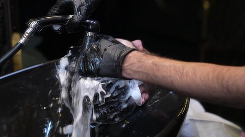 The concept of caring for beauty and appearance, a men's beauty salon, a close-up of a Saudi Arabian Gulf barber washing a customer's hair, hair care routine