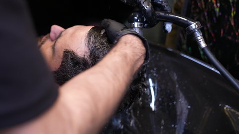 صالون تجميلي رجالي، تقديم خدمات العناية الشخصية، العناية والاهتمام بالجمال والأناقة والمظهر الخارجي، المحافظة على شعر صحي وأنيق، تصويرمقرب  لحلاق عربي خليجي سعودي بغسيل  شعر الزبون، روتين العناية بالشعر