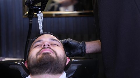 تصفيف الشعر والعناية بمظهره ، الإهتمام بالمظهر الخارجي، العناية بالجمال، تصوير مقرب ليد حلاق عربي خليجي سعودي يقوم بغسيل شعرالزبون ، روتين العناية بالشعر، تقديم خدمات العناية الشخصية