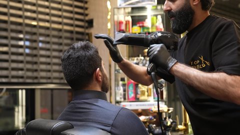 ترتيب وتمشيط الشعر، الإهتمام بالمظهر الخارجي، العناية بالجمال، تصويرمقرب لحلاق عربي خليجي سعودي يقوم بعمل سيشوار لشعر الزبون ، روتين العناية بالشعر، تقديم خدمات العناية الشخصية