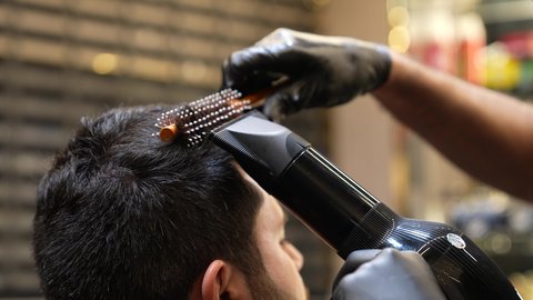 العناية بالجمال, الإهتمام بالمظهر الخارجي، تصويرمقرب ليد حلاق عربي خليجي سعودي يقوم بأستخدام جهاز مجفف الشعر الكهربائي ( السيشوار ) للزبون ، روتين العناية بالشعر، تقديم خدمات العناية الشخصية