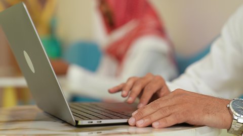 استخدام الأجهزة التقنية الحديثة والمتطورة,إدارة شؤون الأعمال وتنظيمها عبر الاجهزة التقنية, تصوير مقرب ليد رجل عربي خليجي سعودي يرتدي الثوب التقليدي والشماغ يعمل على جهاز الحاسب المحمول