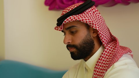 الرد والإجابة على الجوال, تصوير مقرب لرجل عربي خليجي سعودي يرتدي الشماغ والثوب التقليدي يجلس فى احد المقاهي يقوم بإجراء مكالمة هاتفية عبر الهاتف المحمول, دردشات ومحادثات ودية مع الأصدقاء, استخدام الأجهزة التقنية الحديثة