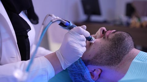 تقديم الخدمات والرعاية الصحية ، جلسة ليزر في عيادة خاصة، سيد عربي عماني خليجي يجلس على كرسي العلاج في موعد بعيادة طبية مختصة بالتنظيف والعناية بالبشرة، طبيبة عربية خليجية عمانية تستخدام احدث التقنيات لعلاج الوجه