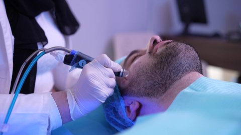 جلسة ليزر في عيادة خاصة، سيد عربي عماني خليجي يجلس على كرسي العلاج في موعد بعيادة طبيبة مختصة بالتنظيف والعناية بالبشرة، طبيبة عربية خليجية عمانية تستخدام احدث التقنيات لعلاج الوجه، تقديم الخدمات والرعاية الصحية