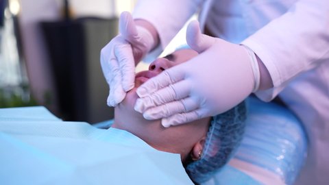 ترطيب وتنظيف وتفتيح الجلد ،استخدام مكونات تجميلية نسائية ، مفهوم العناية والإهتمام بنضارة وتحسين البشرة، سيدة عربية خليجية عمانية ترتدي العباءة تجلس على كرسي العيادة ، طبيبة مختصه فى العناية بالبشرة تضع الكريم المرطب على وجه الزبون