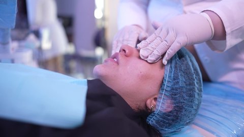 طبيبة عربية خليجية عمانية تضع قطع القطن على العين ، مفهوم العناية والإهتمام بنضارة وتحسين البشرة، جلسات و روتين العناية بالوجه ، مرأة عربية خليجية عمانية في صالون تجميلي نسائي، خطوات تنظيف وتقشير وتفتيح البشرة، إستخدام مكونات تجميلية