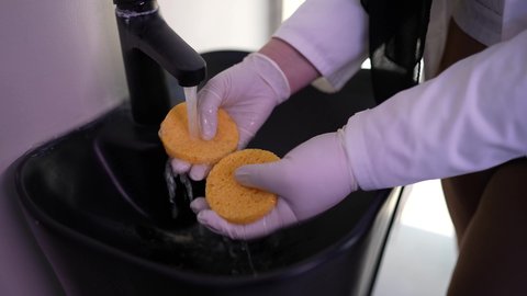 مفهوم العناية والإهتمام بنضارة وتحسين البشرة، ترطيب وتنظيف وتفتيح الجلد، طبيبة عربية خليجية عمانية مختصه فى العناية بالبشرة تقوم بغسل قطع اسفنجيه ، استخدام مكونات تجميلية