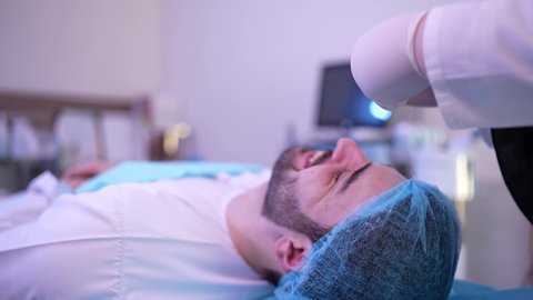 مفهوم العناية والإهتمام بنضارة وتحسين البشرة، ترطيب وتنظيف وتفتيح الجلد، رجل عربي خليجي عماني يرتدي الدشداشة يجلس على كرسي العيادة ، طبيبة مختصه فى العناية بالبشرة تضع قطع قطنية على العين ، استخدام مكونات تجميلية شبابية