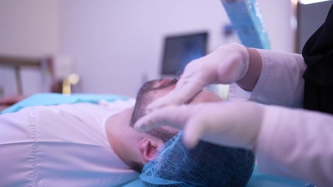 ترطيب وتنظيف وتفتيح الجلد، رجل عربي خليجي عماني يرتدي الدشداشة يجلس على كرسي العيادة ، طبيبة مختصه فى العناية بالبشرة تضع كريم المرطب على وجه الزبون ، مفهوم العناية والإهتمام بنضارة وتحسين البشرة، استخدام مكونات تجميلية شبابية