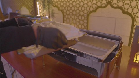 أثاث داخلي راقي لمطعم على الطراز الحديث في المملكة العربية السعودية، صالة مطعم ومقهى بديكورات وألوان جذابة، التصاميم الداخلية للكافيهات والمطاعم، تصوير مقرب ليد طباخ سعودي يقوم باضافه صنف اضافى لطاولة البوفيه المفتوح في العشاء