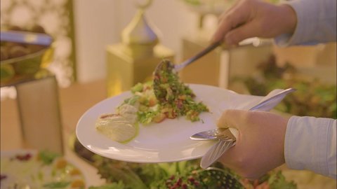 قضاء اوقات ممتعه فى الهواء الطلق ، اطباق متنوعه من المأكولات والمشروبات، مفهوم الخدمة الذاتية في المطاعم السعودية، تصوير مقرب ليد رجل عربي خليجي سعودي يرتدي الزي التقليدي يقوم بسكب الطعام من البوفيه في المطعم