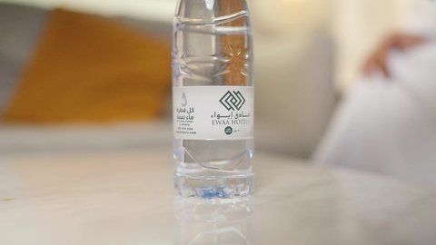 الحفاظ على صحة الكلى ومعالجتها، أهمية شرب الماء النقي للمحافظة على بشرة نضرة، التخلص من سموم الجسم،تصوير مقرب ليد رجل عربي خليجي عماني يرتدي الدشداشه والكمه  يقوم بشرب الماء م قارورة بلاستيكية ، المحافظة على سلامة الجهاز المناعي