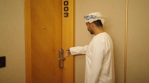 شاليهات راقيه في سلطنه عمان , منتجع سياحي فاخر, الإستعداد لبدء الفعاليات الصيفيه, رجل عربي خليجي عماني يرتدي الدشداشه والكمه يفتح باب غرفة فندقية فاخره , الاستمتاع بالعطلات السياحيه والإجازه الصيفيه