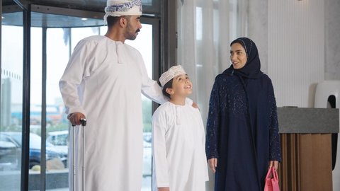 ايماءات السرور والسعاده ، عائله عربية خليجية سعودية تجر حقيبة السفر بالقرب من مكتب الاستقبال في الفندق، الاستمتاع بالاجازه الصيفيه ،سياحة وفندقة وسفر ، قضاء أوقات ممتعة مع العائله