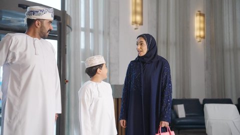 Tourism, hotels, and travel, spending quality time with family, enjoying the summer vacation, a Saudi Arabian Gulf family dragging their suitcase near the hotel reception desk.