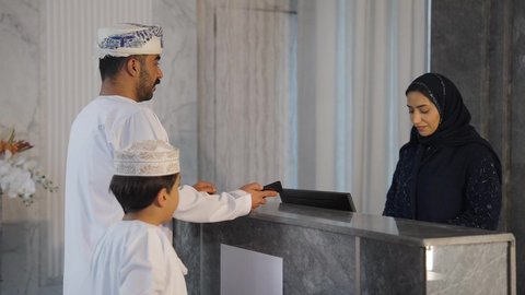إجراءات الحجز والدخول لدى مكتب الاستقبال في الفندق، سيده عربيه خليجيه عمانيه  تعمل في مجال الإستعلامات ، سياحه وفندقه وسفر، إستعلامات وإستفسارات فى خدمة العملاء ، عائله عربية خليجية عمانيه تقوم بالدفع عند الكاشير بطريقة الكترونية بإستخدام بطاقة الإئتمان البنكية