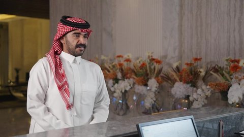 سياحه وفندقه وسفر، إجراءات الحجز والدخول لدى مكتب الاستقبال في الفندق، رجل عربي خليجي سعودي يقوم بالدفع عند الكاشير بطريقة الكترونية بإستخدام بطاقة الإئتمان البنكية، سيده عربية خليجية سعودية ترتدي العباءه والحجاب تعمل في مجال الإستعلامات ،إستعلامات وإستفسارات فى خدمة العملاء