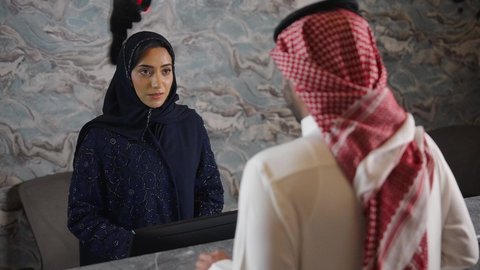 سيده عربية خليجية سعودية ترتدي العباءه والحجاب تعمل في مجال الإستعلامات ،إستعلامات وإستفسارات فى خدمة العملاء ، رجل عربي خليجي سعودي يقوم بالدفع عند الكاشير بطريقة الكترونية بإستخدام بطاقة الإئتمان البنكية