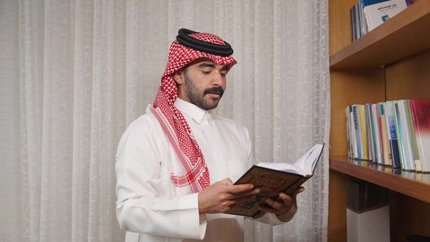 ممارسة الهوايات المفضلة، تنمية المهارات الفكرية ، الاهتمام بالعلم والثقافة والدين ، تعزيز مفهوم المعرفة ، قضاء الوقت بالمطالعة ، رجل عربي خليجي سعودي يرتدي الزى التقليدي مع الشماغ يقف بجانب مكتبه خشبيه ، يأخذ منها كتاب ويبدأ بالقراءه ،  الاستمتاع بالهدوء والراحة داخل المنزل