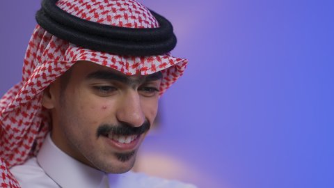 إنجاز المهام المطلوبة عبر اللابتوب، ادارة الأعمال عن بعد،دمج التقنيات المتطوره فى الحياه اليوميه ، التطور والتكنولوجيا الحديثة،وظائف ومهن سعودية، تصوير مقرب لرجل عربي خليجي سعودي يرتدي الزى التقليدي مع الشماغ يجلس على كرسي في غرفة المعيشه ويستخدم جهاز الحاسوب المحمول ، استخدام جهاز اللابتوب