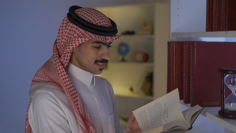 الاستمتاع بقراءة الروايات والقصص ، قضاء الوقت بالمطالعة ، تنمية المهارات الفكرية ، الاستمتاع بالهدوء والراحة داخل المنزل، تعزيز مفهوم الثقافة والمعرفة ،  ممارسة الهوايات المفضلة، تصوير من الجانب لرجل عربي خليجي سعودي يرتدي الزى التقليدي مع الشماغ يجلس في غرفة المعيشة ويقوم بقراءة كتاب