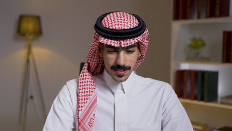 التطور والتكنولوجيا الحديثة،  ادارة الأعمال عن بعد،دمج التقنيات المتطوره فى الحياه اليوميه ، إنجاز المهام المطلوبة عبر اللابتوب، وظائف ومهن سعودية، رجل عربي خليجي سعودي يرتدي الزى التقليدي مع الشماغ يجلس على كرسي في غرفة المعيشه ويستخدم جهاز الحاسوب المحمول ، استخدام جهاز اللابتوب