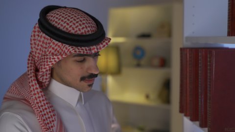 تنمية المهارات الفكرية ، تعزيز مفهوم الثقافة والمعرفة ، قضاء الوقت بالمطالعة ، الاستمتاع بالهدوء والراحة داخل المنزل، ممارسة الهوايات المفضلة، الاستمتاع بقراءة الروايات والقصص ، تصوير من الجانب لرجل عربي خليجي سعودي يرتدي الزى التقليدي مع الشماغ يجلس في غرفة المعيشة ويقوم بقراءة كتاب