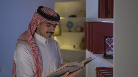 تعزيز مفهوم الثقافة والمعرفة ، قضاء الوقت بالمطالعة ، الاستمتاع بالهدوء والراحة داخل المنزل، ممارسة الهوايات المفضلة، الاستمتاع بقراءة الروايات والقصص ،تنمية المهارات الفكرية ، تصوير من الجانب لرجل عربي خليجي سعودي يرتدي الزى التقليدي مع الشماغ يجلس في غرفة المعيشة ويقوم بقراءة كتاب