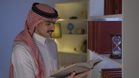 قضاء الوقت بالمطالعة والثقافة، الاستمتاع بالهدوء والراحة داخل المنزل، ممارسة الهوايات المفضلة، الاستمتاع بقراءة الروايات والقصص ،تنمية المهارات الفكرية ، تصوير من الجانب لرجل عربي خليجي سعودي يرتدي الزى التقليدي مع الشماغ يجلس في غرفة المعيشة ويقوم بقراءة كتاب ،تعزيز مفهوم الثقافة والمعرفة