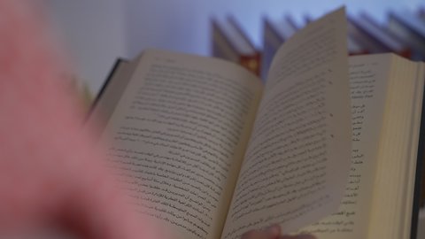 Practicing favorite hobbies, enjoying peace and comfort inside the home, enjoying reading novels and stories, developing intellectual skills, a side view of a Saudi Arabian Gulf man wearing traditional clothing with a shemagh sitting on the sofa in the living room reading a book, spending time reading and culture, promoting the concept of culture and knowledge