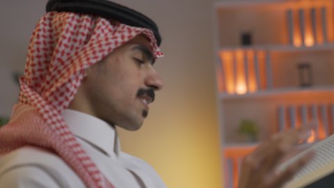 قضاء الوقت بالمطالعة والثقافة، الاستمتاع بقراءة الروايات والقصص ، تعزيز مفهوم الثقافة والمعرفة ،ممارسة الهوايات المفضلة، تصوير من الجانب لرجل عربي خليجي سعودي يرتدي الزى التقليدي مع الشماغ يجلس على الأريكة في غرفة المعيشة ويقوم بقراءة كتاب ،الاستمتاع بالهدوء والراحة داخل المنزل، تنمية المهارات الفكرية