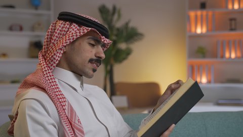الاستمتاع بالهدوء والراحة داخل المنزل، تنمية المهارات الفكرية ، قضاء الوقت بالمطالعة والثقافة، ممارسة الهوايات المفضلة، تصوير من الجانب لرجل عربي خليجي سعودي يرتدي الزى التقليدي مع الشماغ يجلس على الأريكة في غرفة المعيشة ويقوم بقراءة كتاب ، الاستمتاع بقراءة الروايات والقصص ، تعزيز مفهوم الثقافة والمعرفة
