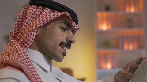 قضاء الوقت بالمطالعة والثقافة، ممارسة الهوايات المفضلة،رجل عربي خليجي سعودي يرتدي الزى التقليدي مع الشماغ يجلس على الأريكة في غرفة المعيشة ويقوم بقراءة كتاب ، الاستمتاع بقراءة الروايات والقصص ، تعزيز مفهوم الثقافة والمعرفة ، تنمية المهارات الفكرية ،الاستمتاع بالهدوء والراحة داخل المنزل