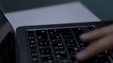 دمج التقنيات المتطوره فى الحياه اليوميه ، وظائف ومهن سعودية، ادارة الأعمال عن بعد، إنجاز المهام المطلوبة عبر اللابتوب، التطور والتكنولوجيا الحديثة، تصوير مقرب ليد رجل عربي خليجي سعودي يرتدي الزى التقليدي مع الشماغ يجلس على اريكه في غرفة مظلمه ويستخدم جهاز الحاسوب المحمول ، استخدام جهاز اللابتوب