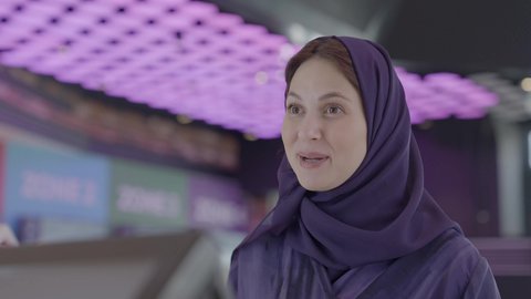 Recreational activities, gestures of happiness and joy, preparing to enter the exhibition hall, close-up shot of a Saudi Arabian Gulf woman inquiring about something, cinema and theater.