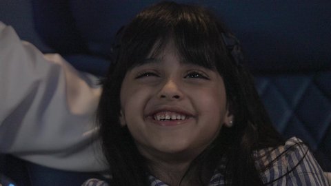 قضاء أوقات ممتعة ومسلية في الخارج، الاستمتاع في عطلة نهاية الإسبوع، متابعة الأفلام والسينما والمسلسلات،تصوير مقرب لفتاة عريية خليجية سعودية مبتسمة تقوم بمشاهدة الأفلام  بتعابير وايماءات الاندماج و السرور