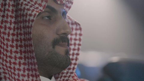 حضور الفعاليات والعروض السينمائية، تصوير مقرب لرجل عربي خليجي سعودي في صالة السينما يرتدي الزي السعودي التقليدي يحمل بيده دلو الفشار، أنشطة ترفيهية، قضاء أوقات ممتعة، صالة العرض