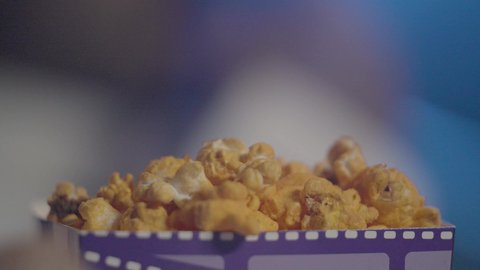 الترفيه عن النفس وقضاء وقت ممتع، تصوير مقرب ليد رجل عربي خليجي سعودي يقوم بتناول دلو من الفوشار، أفلام وسينما، قضاء أوقات ممتعة