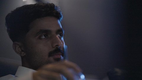 نشاط فردي ترفيهي، الاستمتاع بتناول المشروبات، تصوير مقرب لشاب عربي خليجي سعودي يرتدي الزي التقليدي يقوم بمشاهدة الأفلام بايماءات الاندماج و التركيز، قضاء أوقات ممتعة ومسلية ، عطلة نهاية الإسبوع